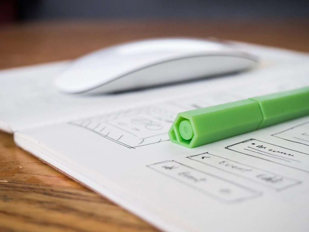 Website layout wireframes sketched beside a phone